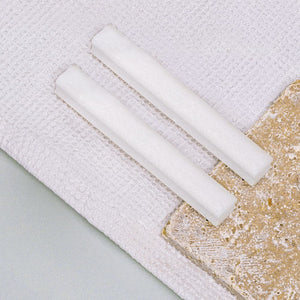 Shower+ Totes Meer Salz Sticks, liegend auf einer Stoffunterlage.